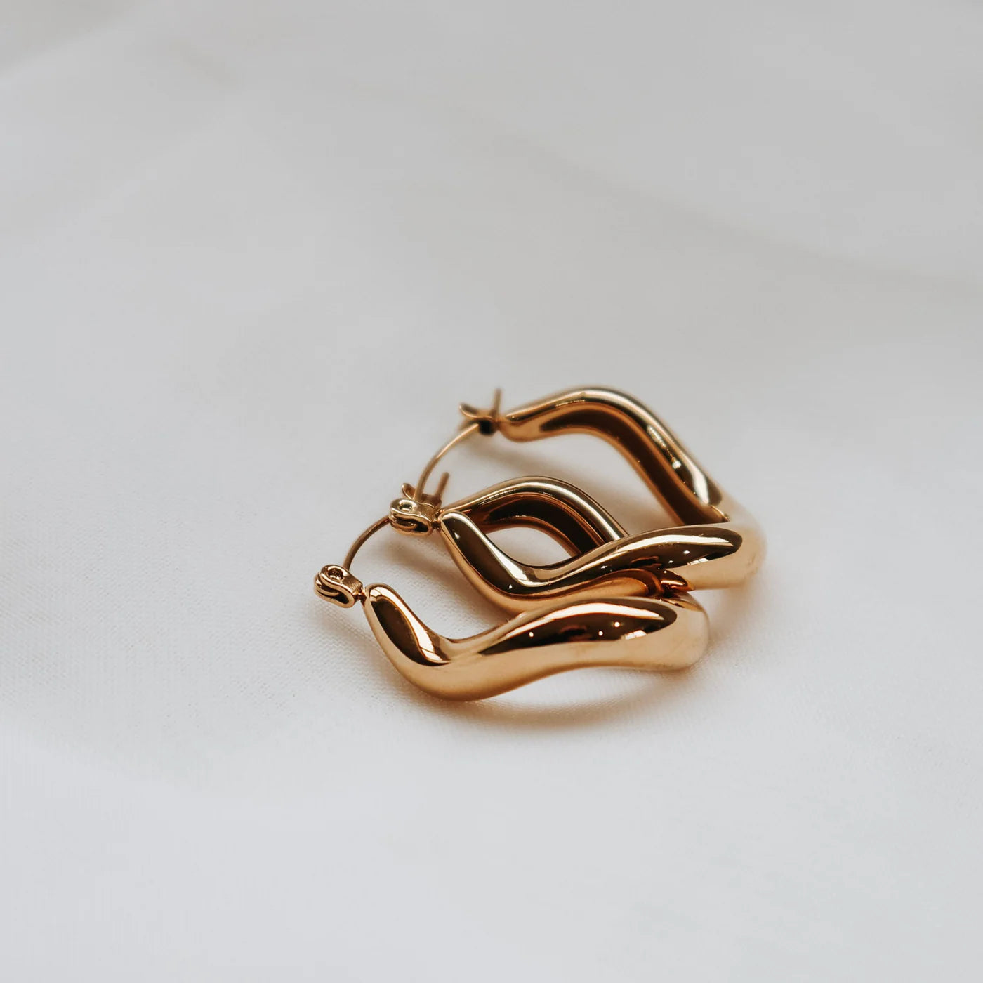 Gold hoop earrings on a light gray background